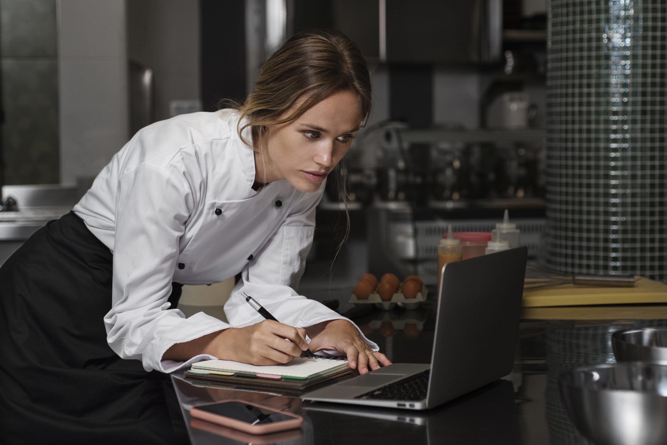 woman standing over her computer with a clipboard
